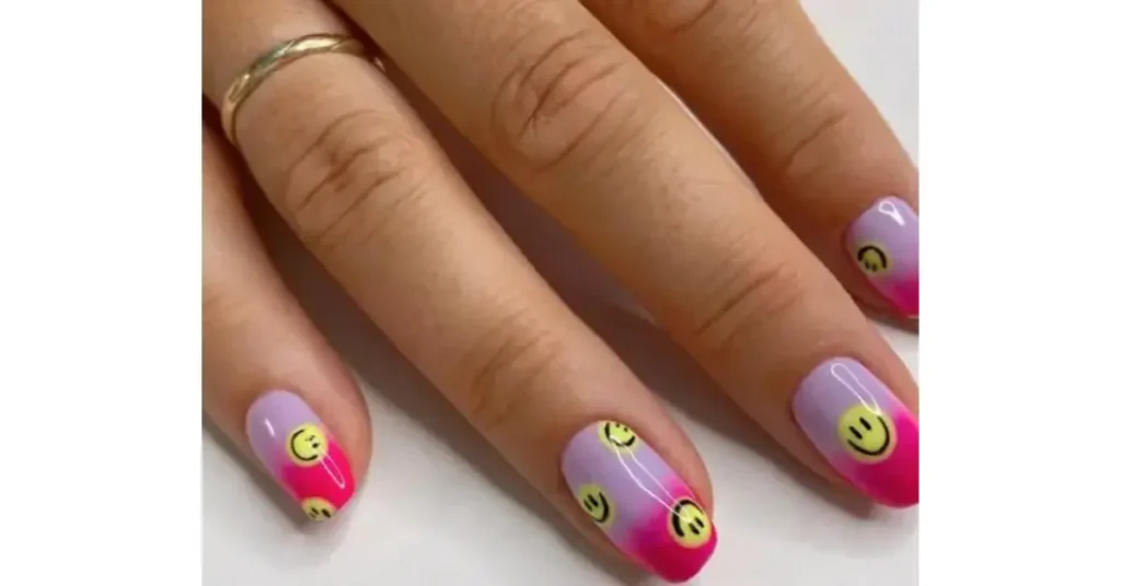 46. Pink and purple pastel ombre acrylic nails with yellow smiley faces