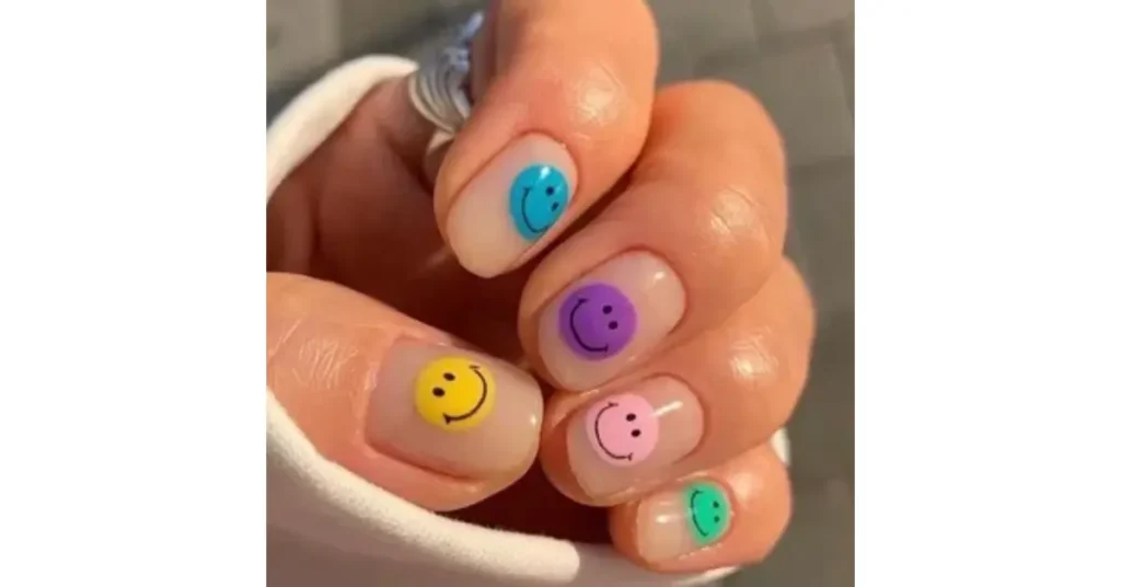 45. Multicoloured smiley faces on nude pink acrylic nails